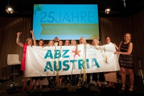 Die beiden Geschäftsführerinnen von ABZ*AUSTRIA ganz links: Manuela Vollmann und Daniela Schallert mit Kolleginnen Geschäftsführung und leitende Angestellte von ABZ*AUSTRIA halten ein großes Plakat mit dem ABZ*AUSTRIA-Logo.