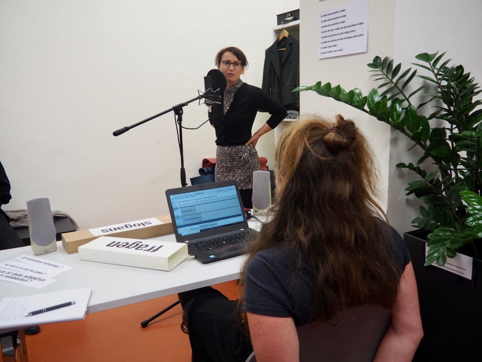 So unterschiedlich die Meinungen und der Umgang mit dem Thema Emanzipation der Frauen sind, eins eint sie, sie alle beschäftigt es und alle haben ihre Erfahrungen mit Benachteiligung oder Unterdrückung gemacht. Eine Frau steht und spricht ins Mikrofone, eine andere sitzt und schaut sich die Aufnahme auf dem Laptop an.