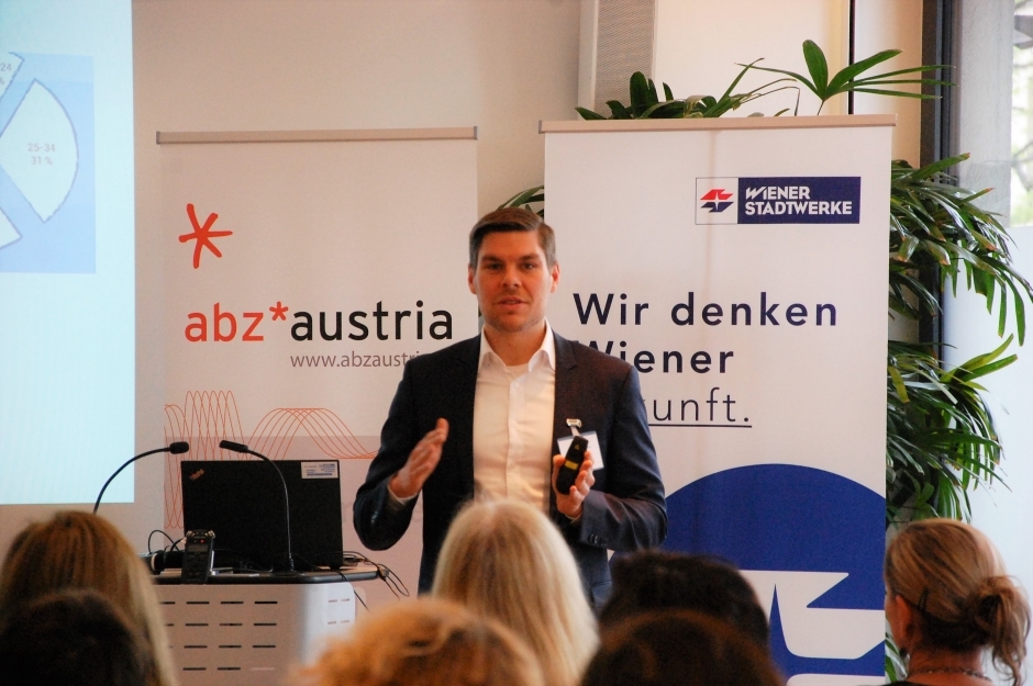 Reinhard Birke, Geschäftsführer von 'Upstream – next level mobility'/Wiener Stadtwerke Holding AG Reinhard Birke spricht vor dem Publikum. Er trägt ein schwarzes Sakko. Hinter ihm befinden sich zwei Roll-ups.