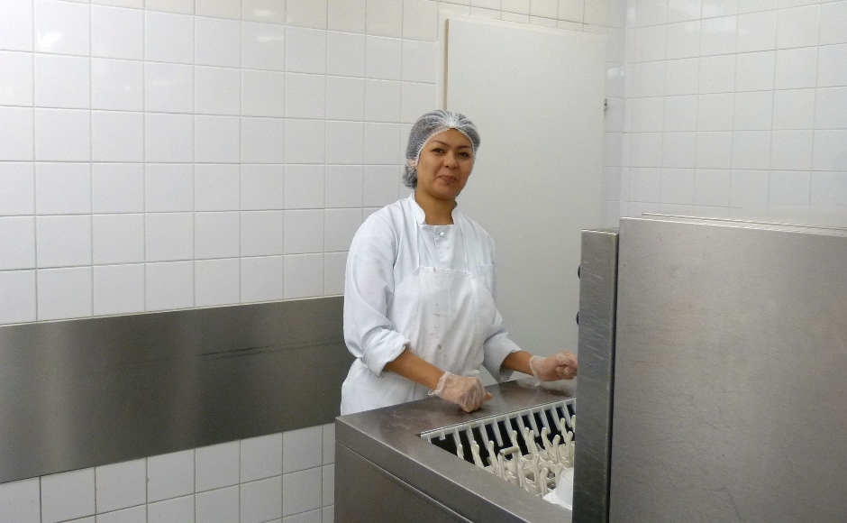 Arefa Hossaini ist über ein Schnupperpraktikum an den Job bei der Wiener Städtischen gekommen: "Ich habe am Kompetenzcheck von ABZ*AUSTRIA teilgenommen" Eine Frau mit einem Haarnetz auf dem Kopf lächelt in die Kamera. Sie steht neben einem Gastro-Geschirrspüler.