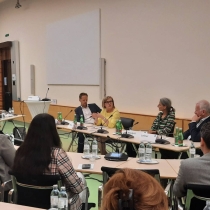 Tagungsteilnehmer*innen sitzen in einem Tisch-Kreis und diskutieren. Manuela Vollmann spricht. ABZ*AUSTRIA Tagung Men in care