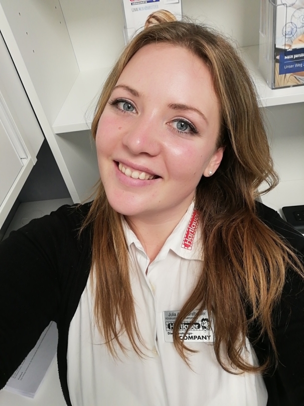 Julia Grafhaider lächelt strahlend in die Kamera. Sie trägt ihre Hartlauer-Dienstkleidung