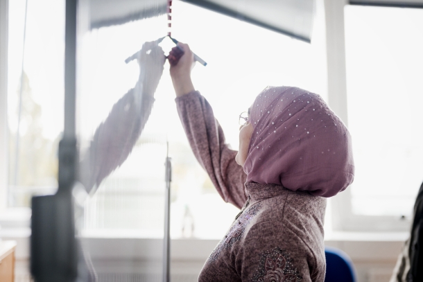 Lehrerin mit Kopftuch schreibt auf eine Tafel